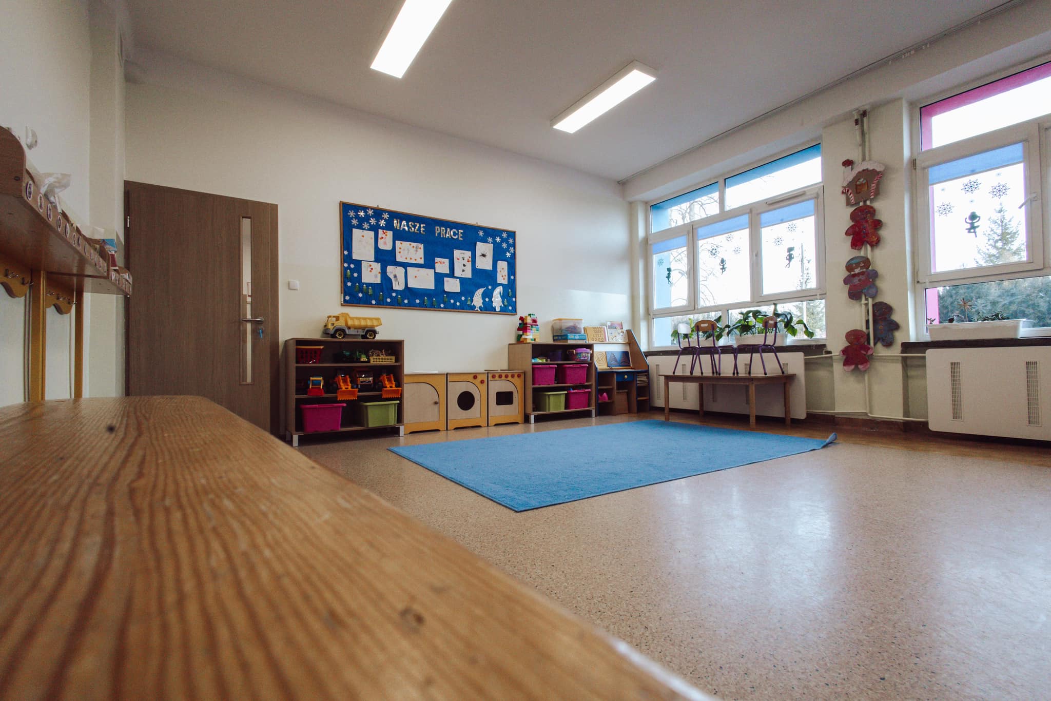 Druga sala oddziału przedszkolnego, z miejscem do zabawy i pracy przy stolikach.